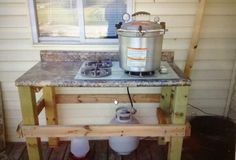 a stove top sitting on top of a wooden table next to a building with windows