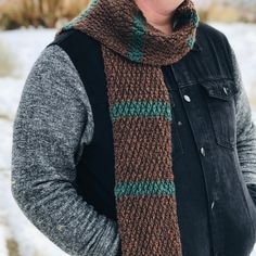 a woman wearing a knitted scarf in brown, green and black with her hands on her hips