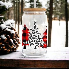 a glass jar with a christmas tree painted on it