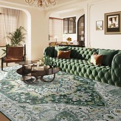 a green couch sitting on top of a rug in a living room under a chandelier