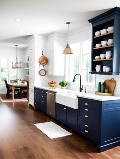 a kitchen with blue cabinets and white walls, wooden floors and open shelving above the sink