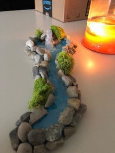 there is a small river in the rocks next to a lit candle on the table