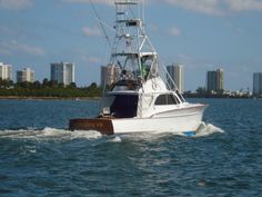 a white boat traveling through the water with buildings in the backgrouds behind it