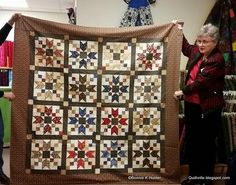 an older woman holding up a quilt in front of her