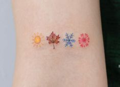 three different colored leaves on the side of a woman's arm, one with sun and snowflakes