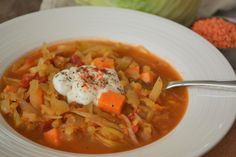 a bowl of soup with carrots, onions and sour cream on the top is ready to be eaten