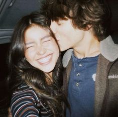 a young man and woman kissing in the back of a car