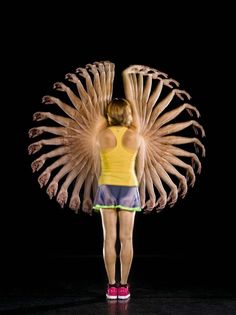 a woman standing in front of a black background with her hands on the back of her head