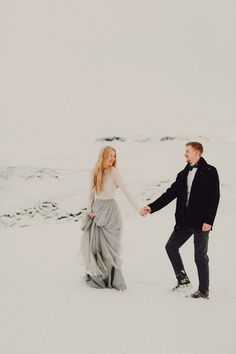 a man and woman holding hands in the snow