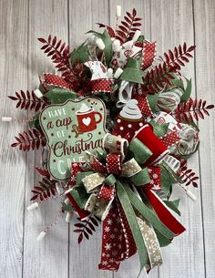 a christmas wreath with coffee mugs and holly leaves on the front door hanger