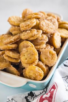 a bowl filled with fried bananas on top of a blue and white table cloth next to a napkin