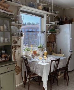 a kitchen with a table and chairs in front of a window filled with dishes on it