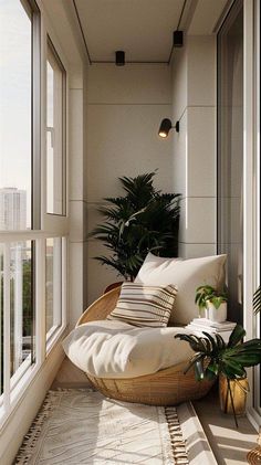 a room with some plants and pillows on the floor next to a large glass window