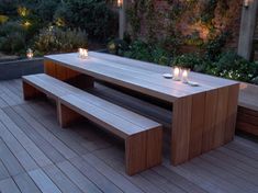 a wooden table with candles on it in the middle of a decked garden area