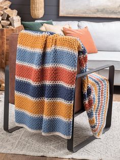 a multicolored blanket sitting on top of a chair in front of a couch