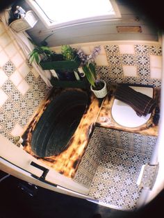 an aerial view of a toilet in a tiled room with flowers and potted plants