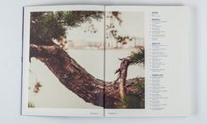 an open book with pictures of trees and water in the background on a white surface