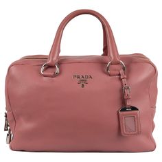 Expertly crafted with soft supple leather in pink, the Prada Boston Handbag is the ultimate everyday accessory. Its ample size comfortably holds all your essentials, while the double zipper detail and silver hardware add a touch of elegance. Complete with a lock, key, and leather tag, this bag is both functional and stylish. Inclusion: Dust bag. Remarks: There is a small spot on the back side. Height:24;Width:33.5;Depth:13.5;Handle Drop:8 Leather Tag, Novelty Bags, Everyday Accessories, Zipper Detail, Spot On, Silver Hardware, Fashion Handbags, Boston, Prada