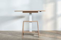 a wooden table sitting on top of a cement floor next to a white wall and window