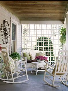 a porch with rocking chairs and potted plants on the front porch, next to a pergolated screen door