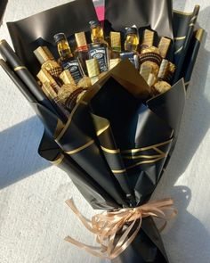 a bouquet of liquor bottles wrapped in black paper and tied with gold ribbon on the table