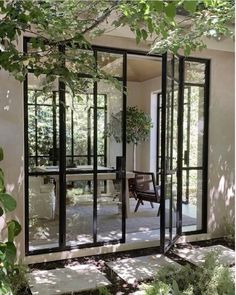 an open glass door leading to a patio area with chairs and potted plants in the background