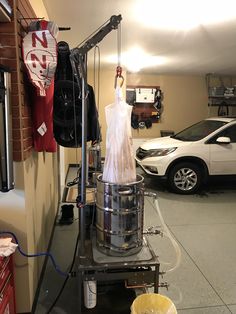 a car parked in a garage next to a table with an object on it and another item hanging from the ceiling