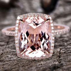 a pink diamond ring sitting on top of a piece of wood with diamonds around it