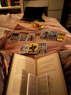 an open book sitting on top of a bed next to a pile of playing cards