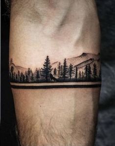 a man's arm with trees and mountains tattoo on the left side of his arm