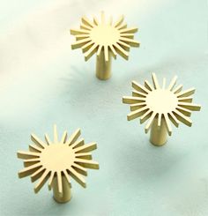 three golden metal knobs on a light blue surface with sunburst design in the middle