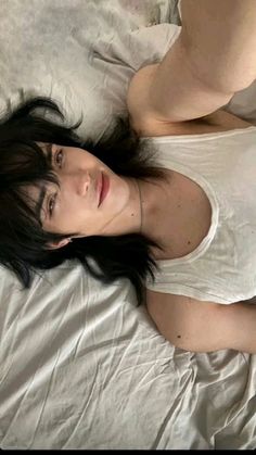 a woman laying on top of a bed next to a white sheet and pillow cover