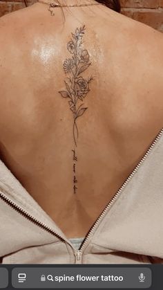 the back of a woman's neck with flowers tattooed on her lower back and upper part