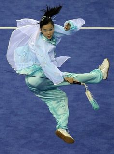 a woman is performing on the tennis court with her leg in the air while holding an umbrella