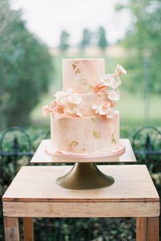 a three tiered cake sitting on top of a wooden table