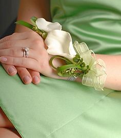 a woman in a green dress holding a white flower and ring on her left hand