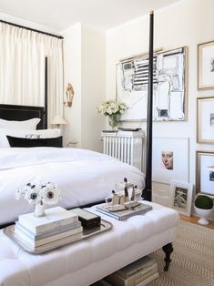 a bedroom with white bedding and pictures on the wall