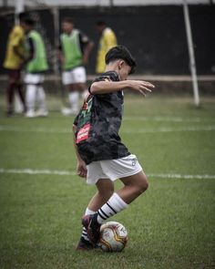 a young boy kicking a soccer ball on a field