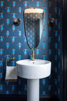 a white sink sitting under a bathroom mirror next to a wall mounted faucet