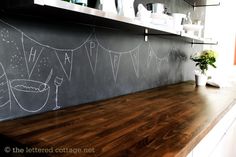 a chalkboard wall in the kitchen with bunting flags on it and a potted plant