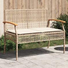 a wicker bench sitting on top of a brick patio next to a wooden fence