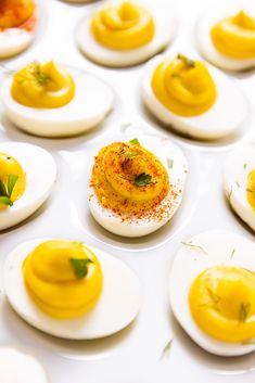 several deviled eggs with different toppings on them sitting on a white table top