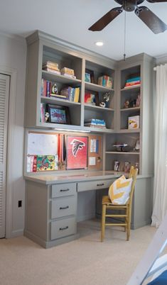 a bedroom with a bed, desk and bookcases on the wall next to a ceiling fan