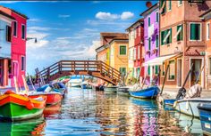 several boats are docked in the water next to colorful buildings and a bridge over it