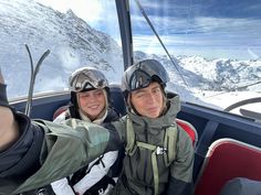 two people taking a selfie in the back of a helicopter with mountains in the background