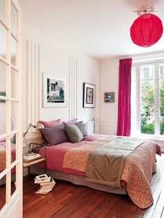 a bed room with a neatly made bed next to a window