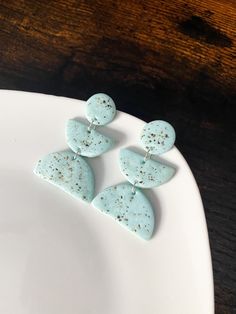 three blue earrings are on a white plate