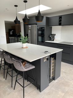 a kitchen with an island and two stools in front of the counter top that has a potted plant on it