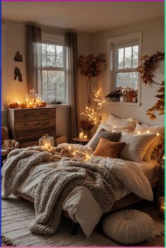 a bedroom with candles and blankets on the bed in front of two windows, surrounded by foliage