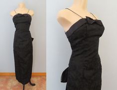 "Black cocktail dress from the 90's era! Inky black scroll floral design fabric and trimmed with black satin. Spaghetti straps with satin bodice and large black bow. Low cut back with large bow. Zip down back entry. Floor length. Lined inside. Estimated to fit like a modern size extra small. Please double-check measurements below.  MEASUREMENTS--Taken with garment laying flat, in inches, doubled: Bust: 34\" Waist: 25\" Hips: 36\"  Shoulders: 8\"  Length: 57\" Fabric: Acetate, nylon zipper Label/Era: JReynolds Designs / 1990 Stated Size: 5/6 Condition: Excellent vintage condition. Freshly laundered. No known issues.  ★ The \"fits like\" size is just an estimate, and vintage sizing can vary from modern sizing. Please use measurements to ensure proper fit. ★ Shop the entire shop here: https:/ Black Bow Evening Dress For Formal Occasions, Black Formal Evening Dress With Bow, Fitted Dress With Bow For Black-tie Events, Fitted Evening Dress With Bow Straps, Black Evening Dress With Bow For Gala, Fitted Evening Dress With Bow For Cocktails, Low Cut Black Dress, Entry Floor, Statement Dress